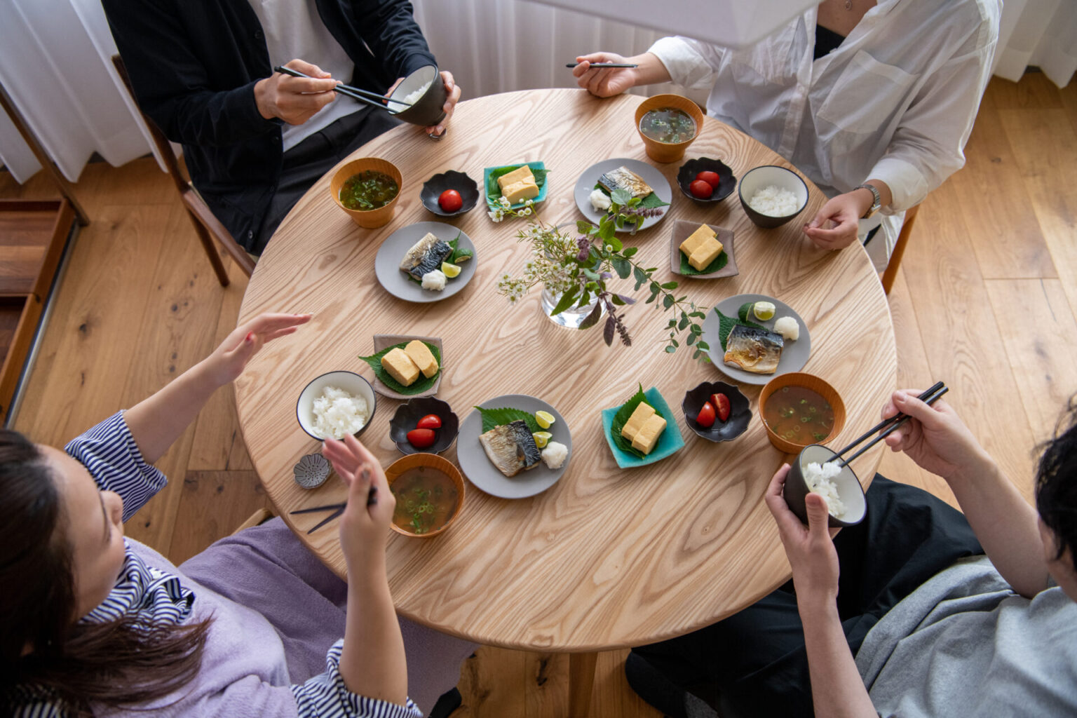 直径100cmの丸テーブルを使って4人で食事をしたイメージ